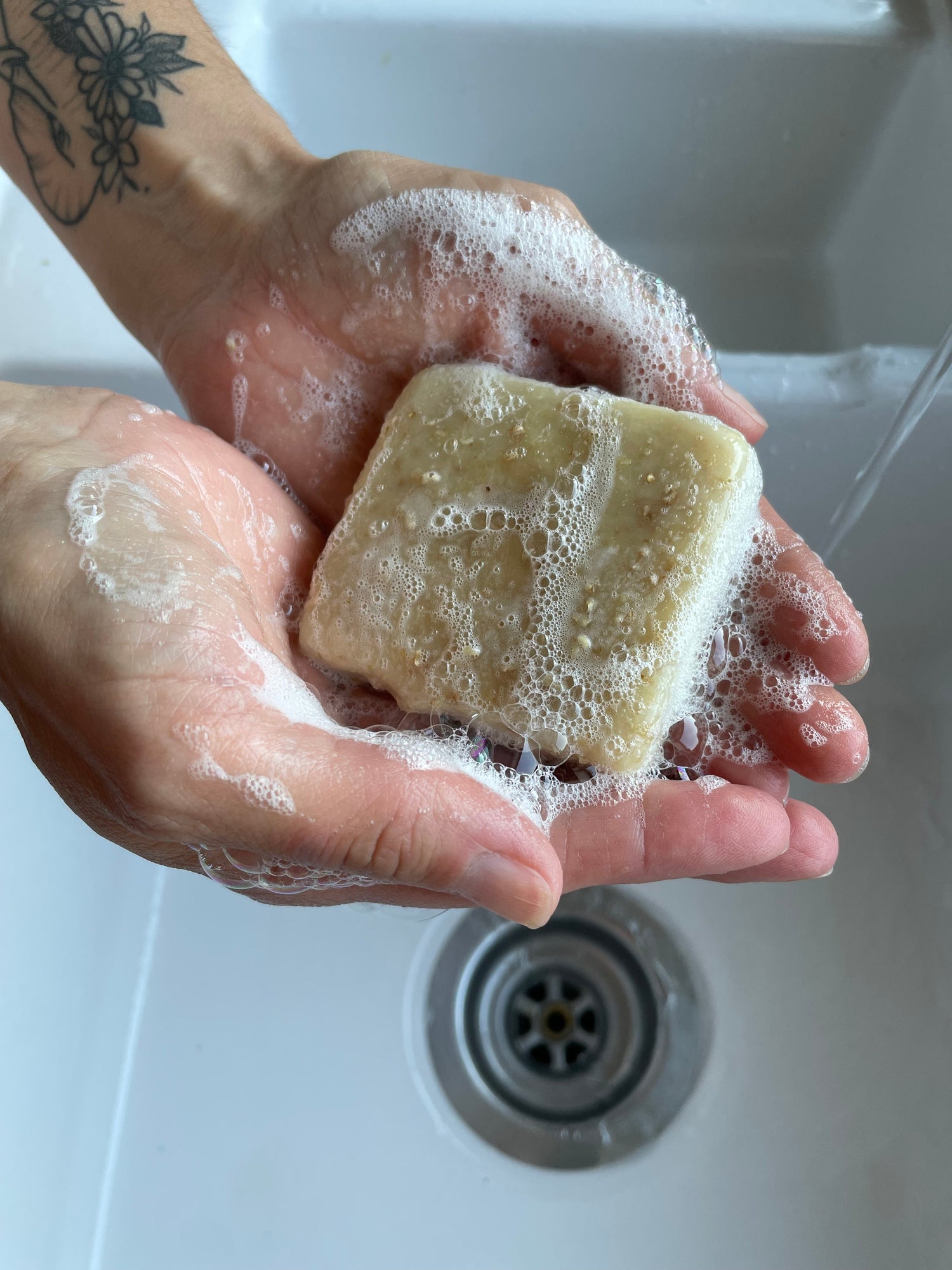 Hands holding lathered soap over a basin.