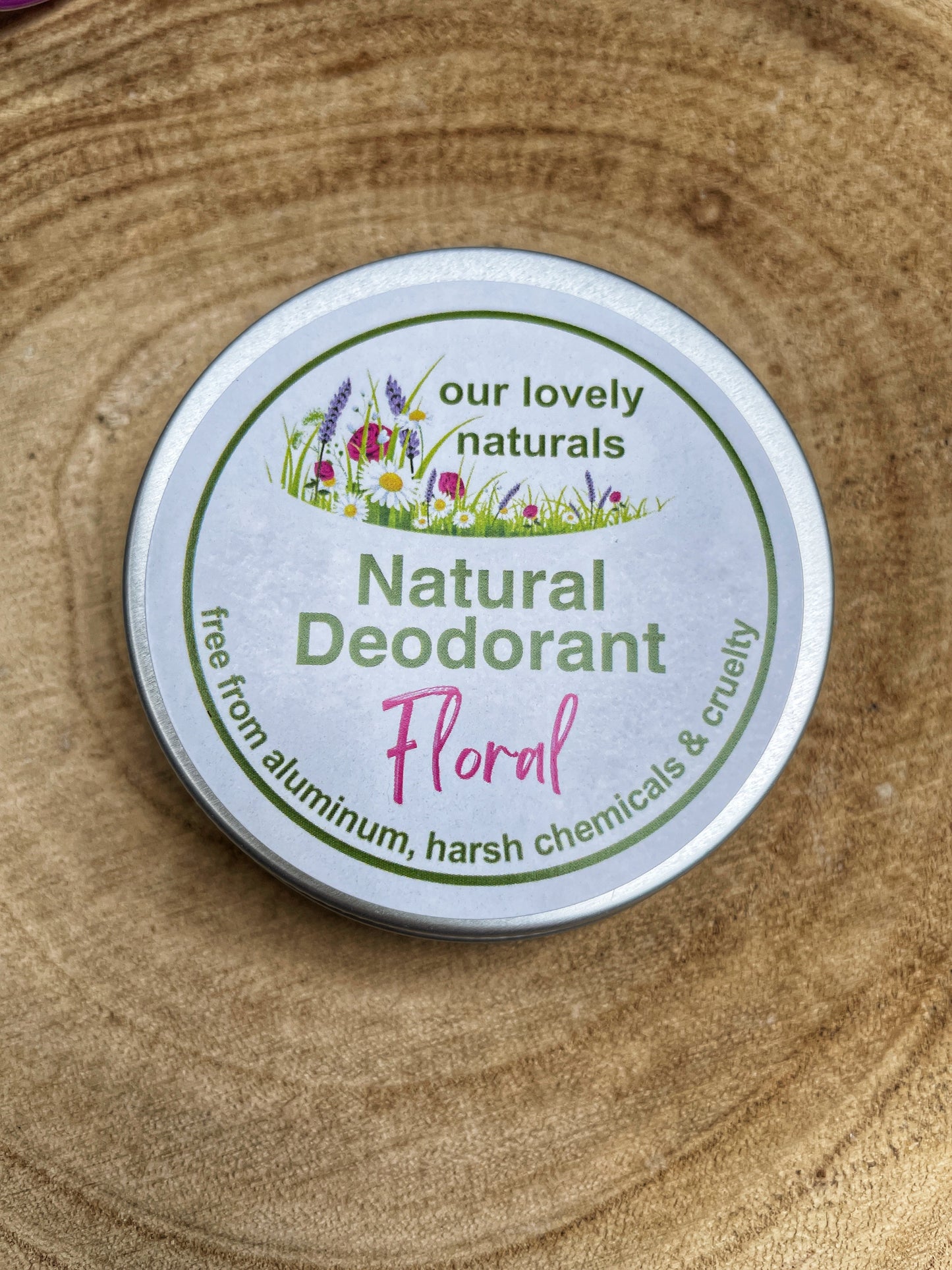 Tin of handmade, sustainable, plastic free, chemical free floral natural deodorant on a wooden board