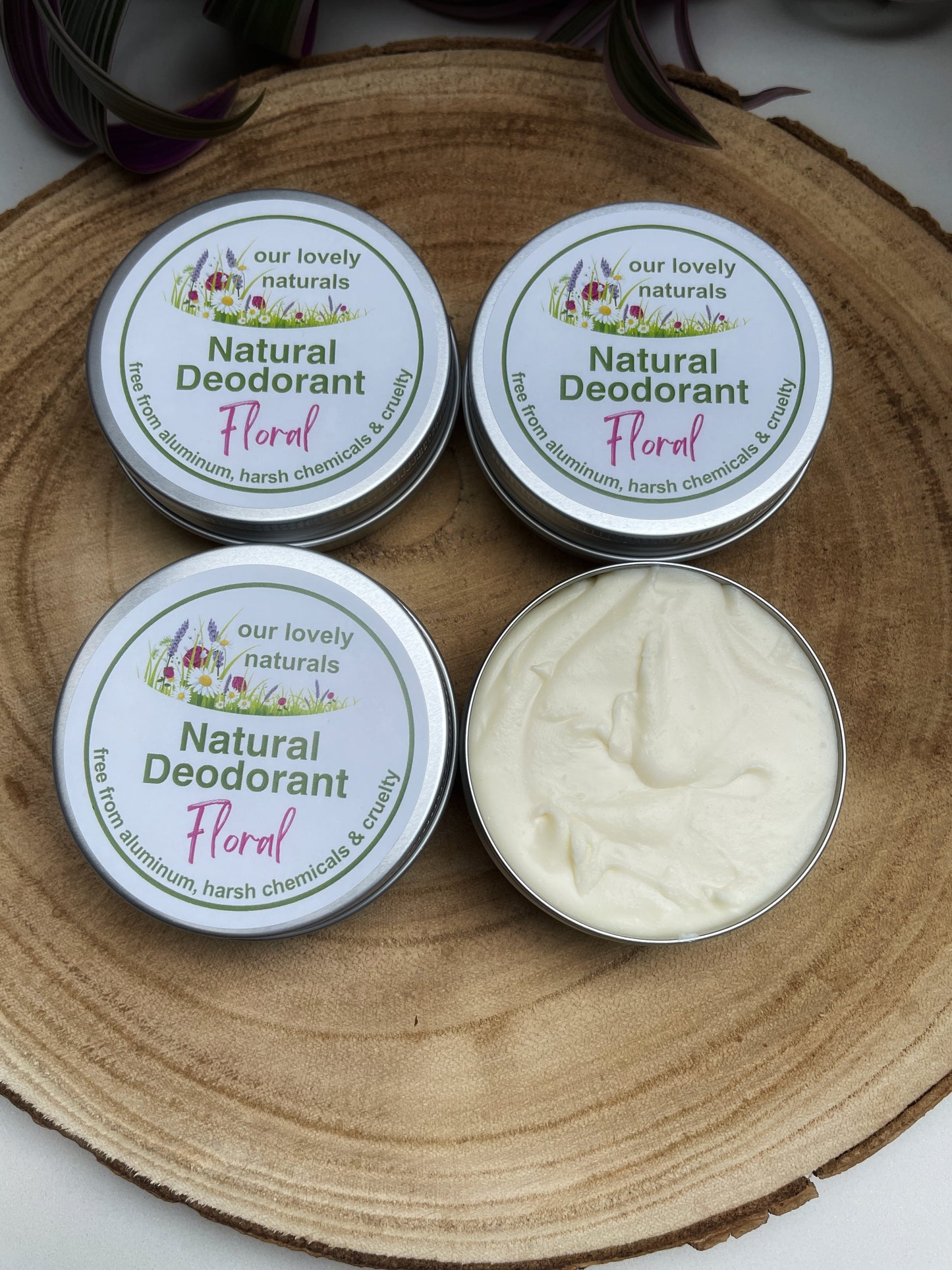 Four tins of handmade, sustainable, plastic free, chemical free floral natural deodorant on a wooden board