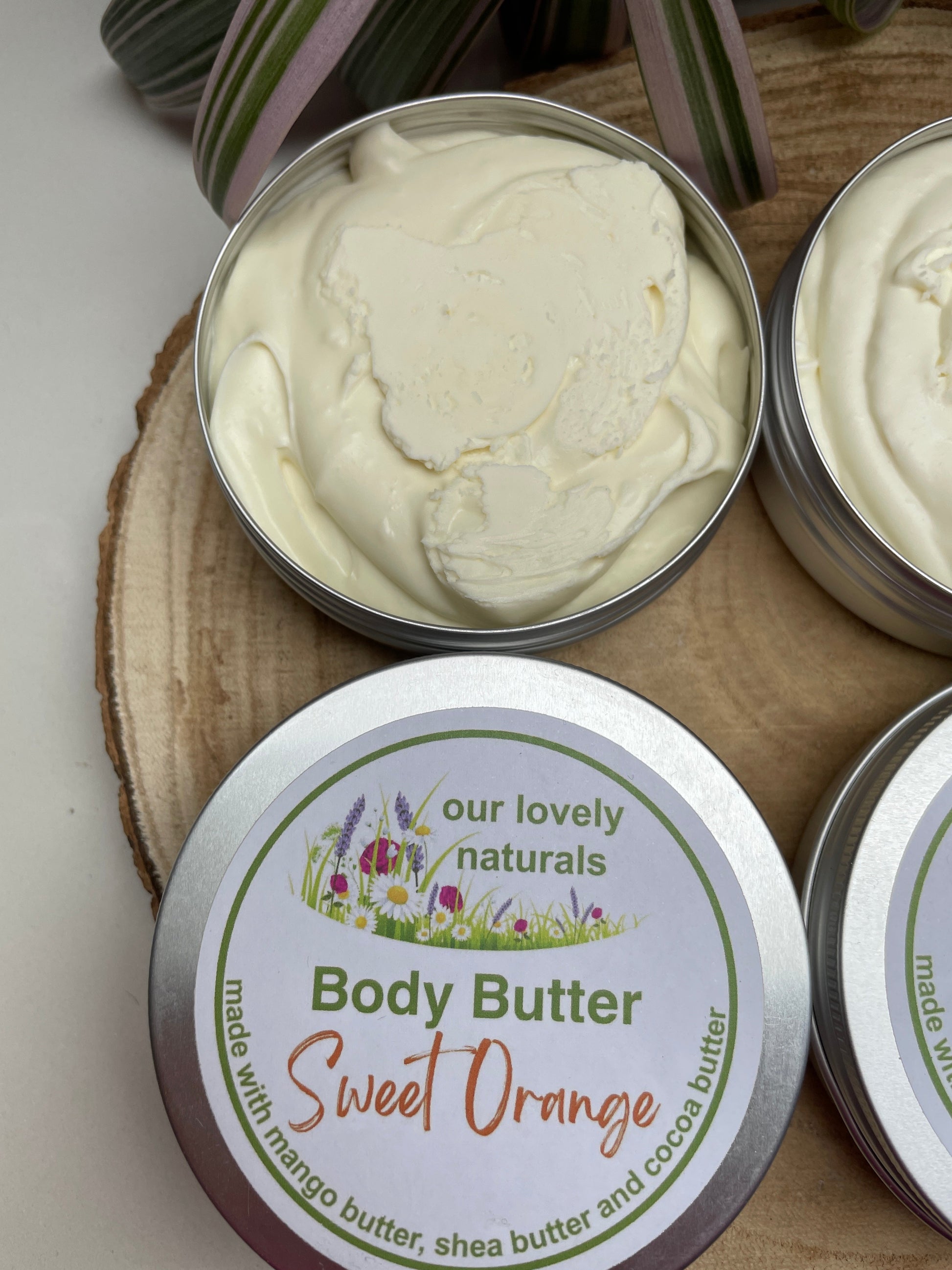 two tins of completely natural, handmade, Sweet Orange body butter on a wooden board