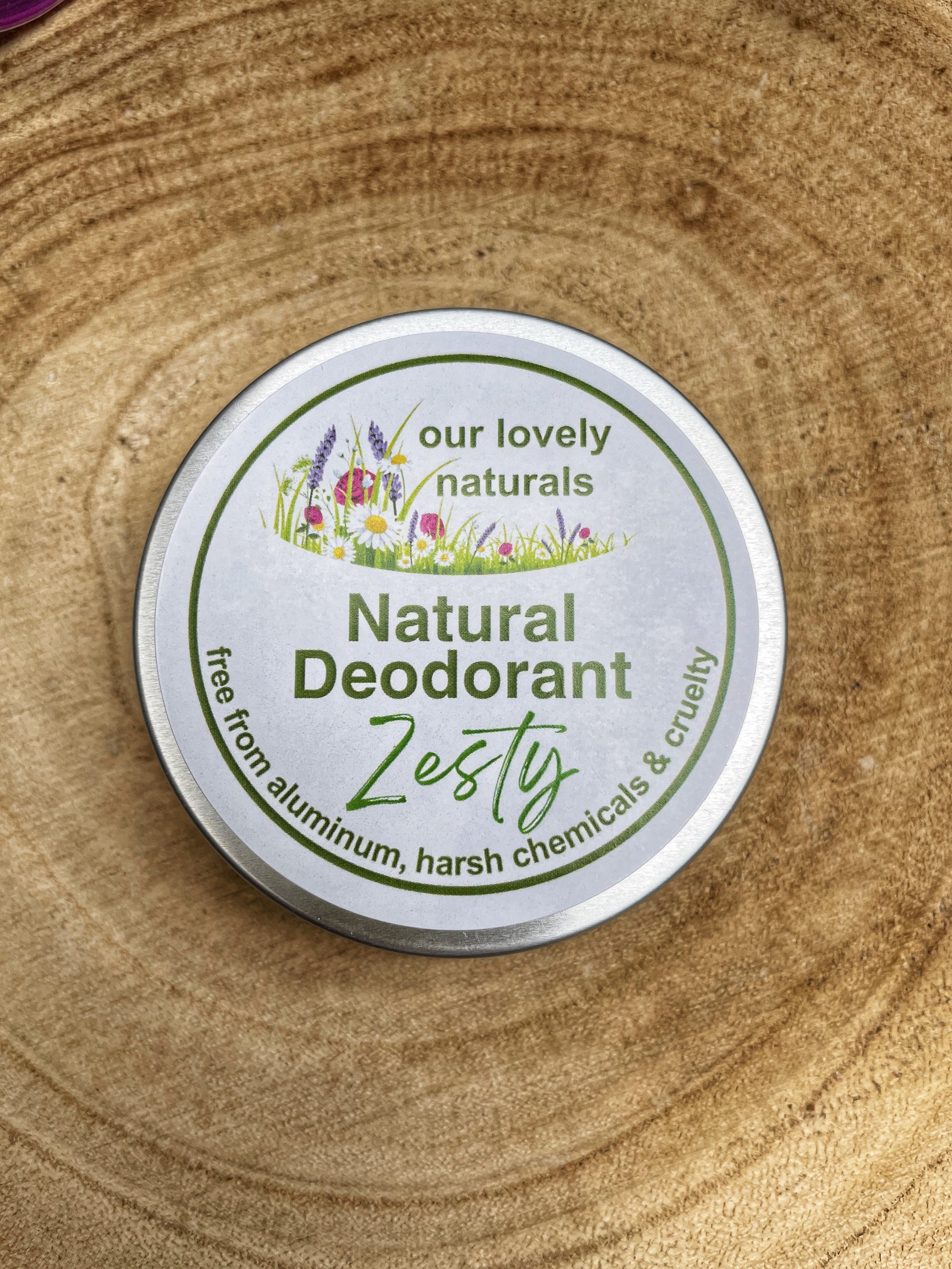 Tin if handmade, sustainable, eco friendly, plastic free zesty natural deodorant on a wooden board